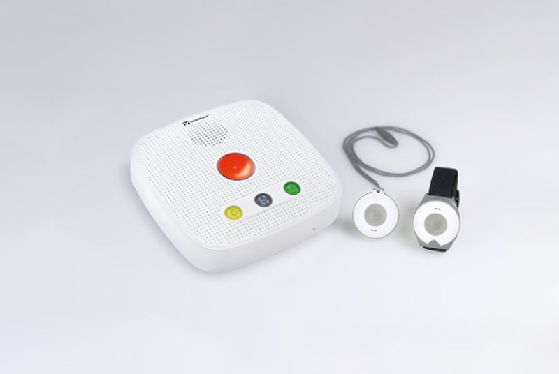 Hausnotrufgerät mit rotem Knopf und zwei runden Notfallsendern, einer mit Armband, einer mit Halsband