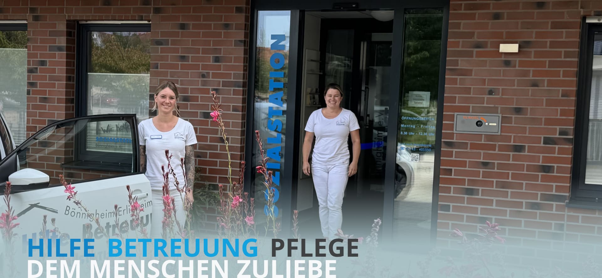 Zwei Frauen in weißer Arbeitskleidung stehen vor einem Gebäude mit der Aufschrift "SOZIALSTATION" neben einem weißen Auto mit der Aufschrift "Hilfe Betreuung SOZIALSTATION"